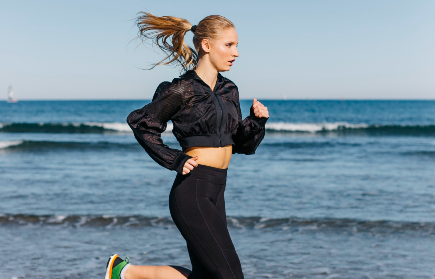 A woman running on the beach near the ocean.