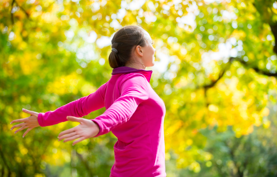 A woman in pink shirt with arms outstretched.