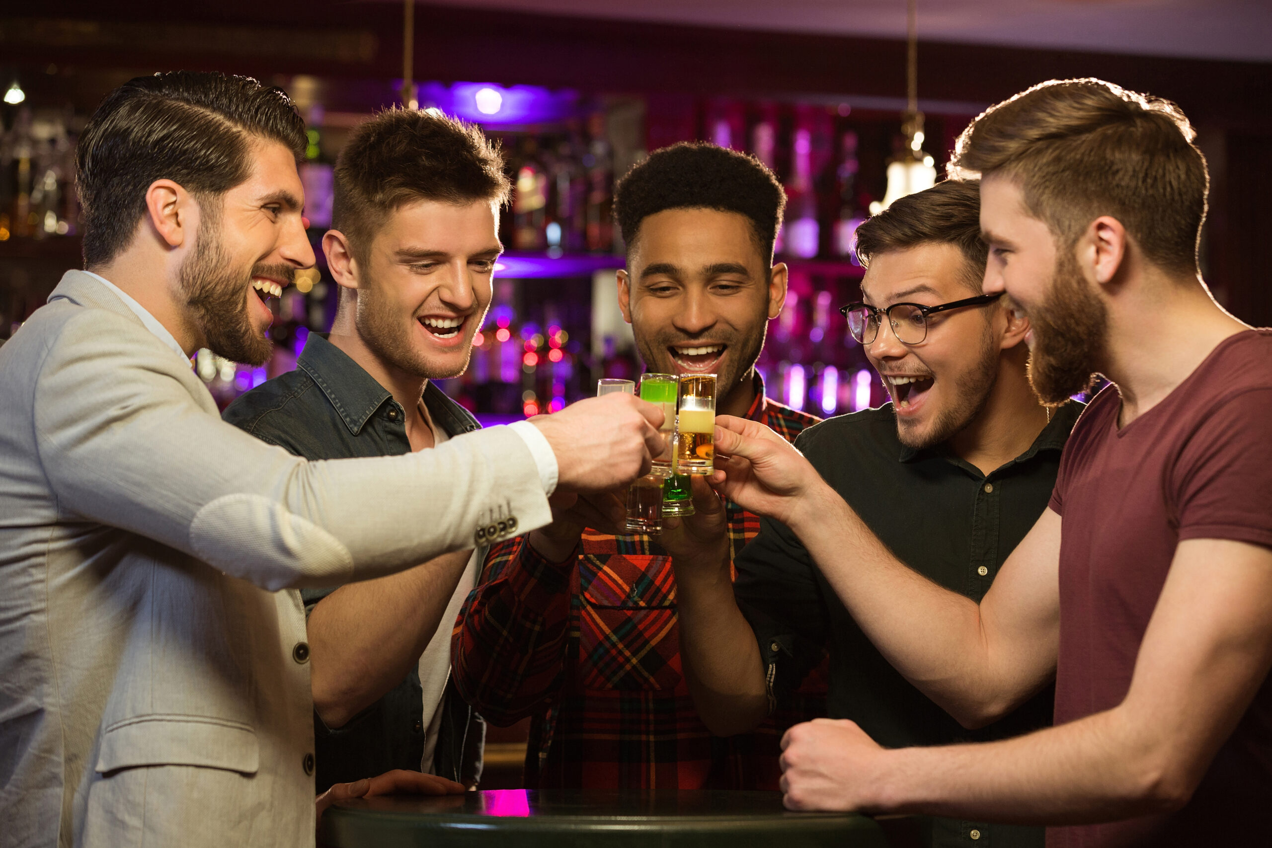 A group of men are toasting at the bar.