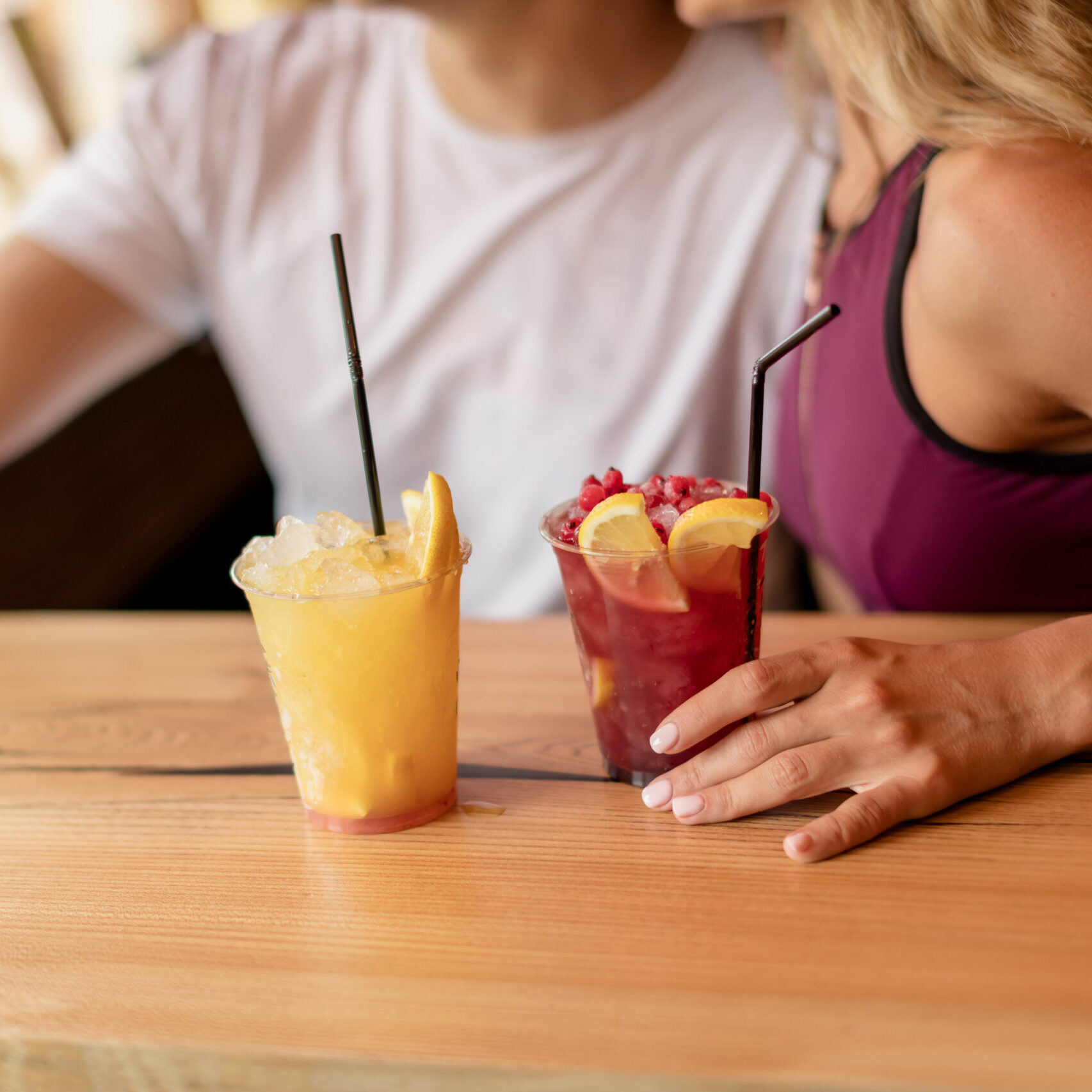 A woman sitting at the table with two drinks.